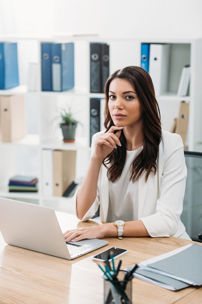 businesswoman sitting at table with laptop in office
